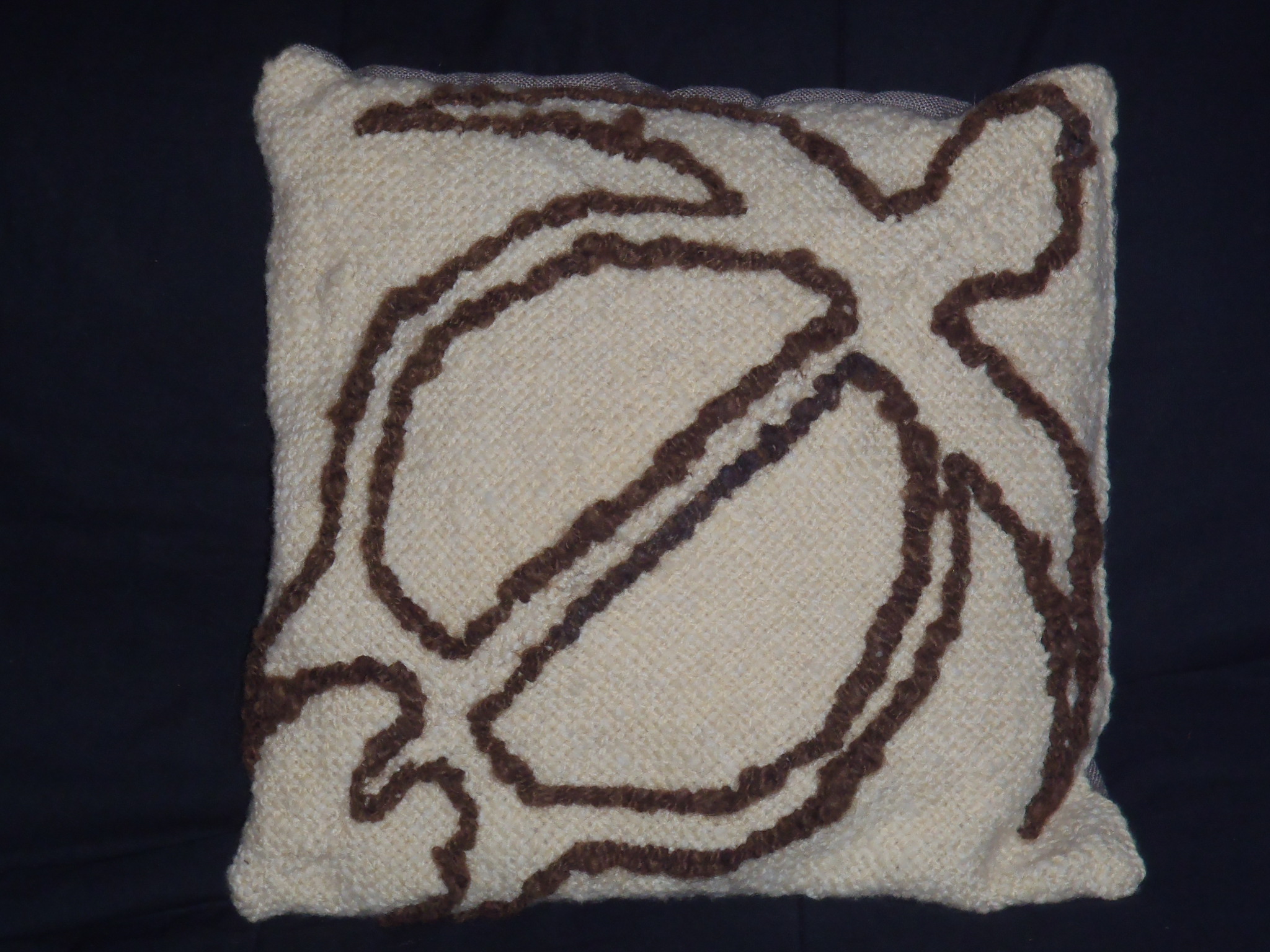 Photo of wool filled cushion with woven wool embroidered cover. Turtle petroglyph pattern embroidered on cover. .